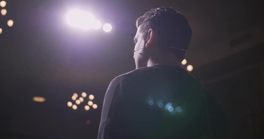 A man is speaking on stage and moving his hands