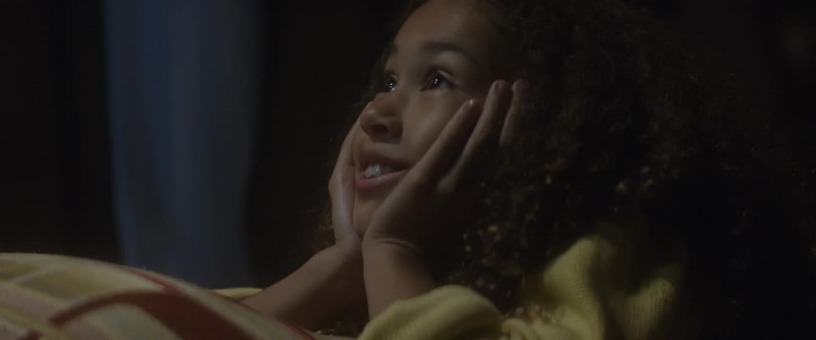 Child lays in bed smiling