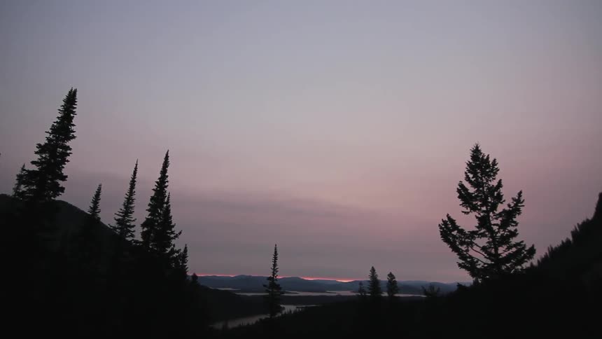 A mountain landscape is shown at sunset