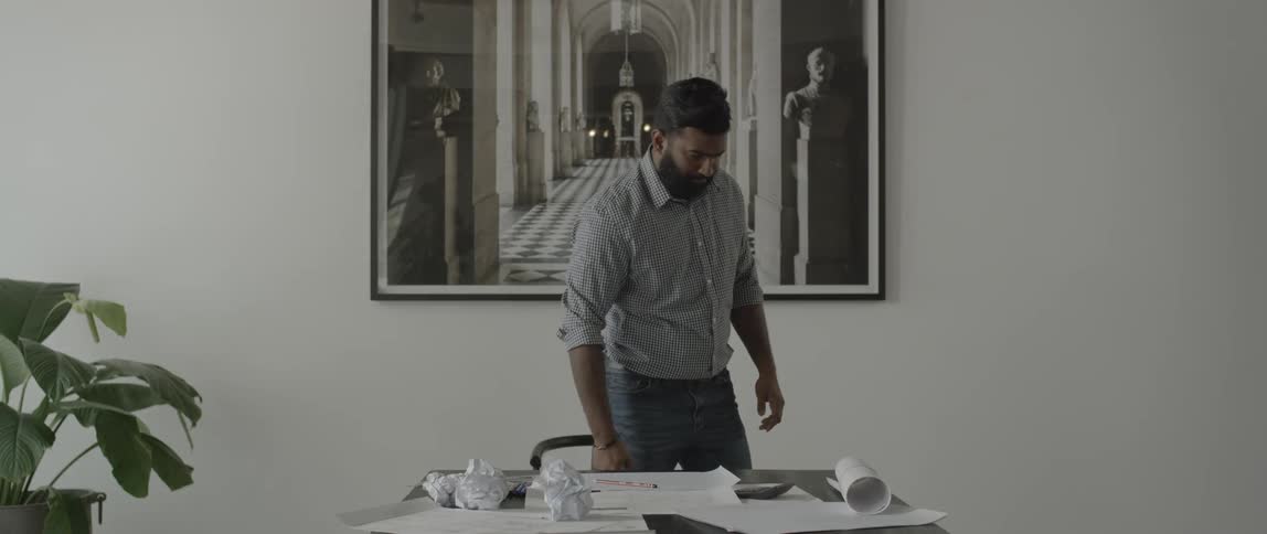 A man leans over a table with crumpled papers