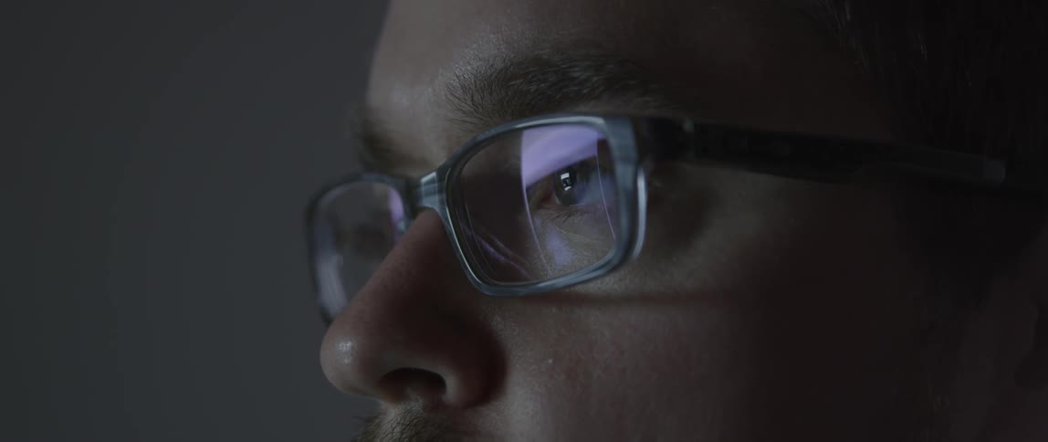 A man wearing glasses is looking at a computer screen
