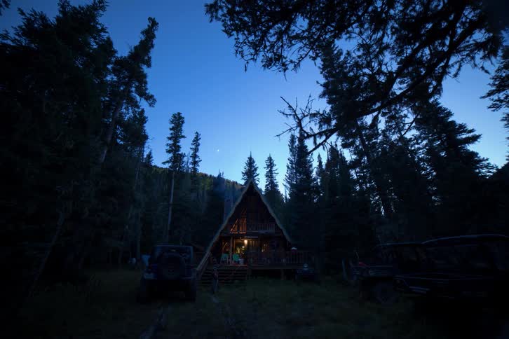 A cabin in a forest as the sun sets