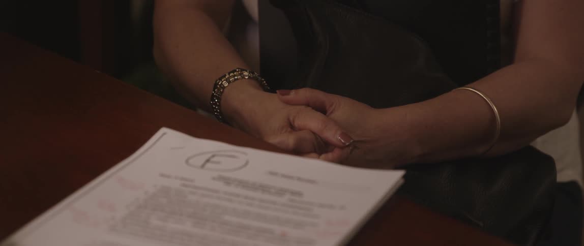 Person sitting at a desk clasping their hands