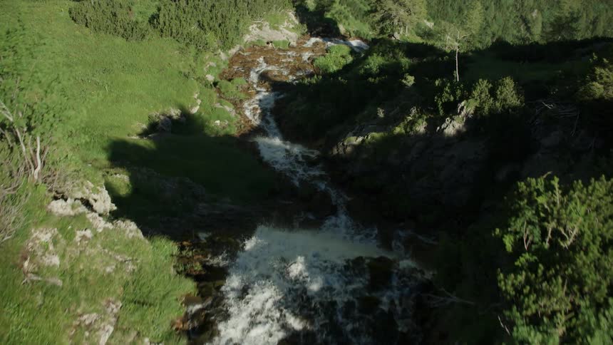 A stream runs to the edge of the mountain top creating a waterfall