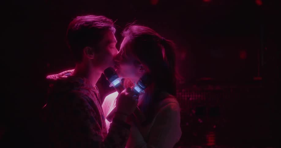 A man and woman holding microphones kiss