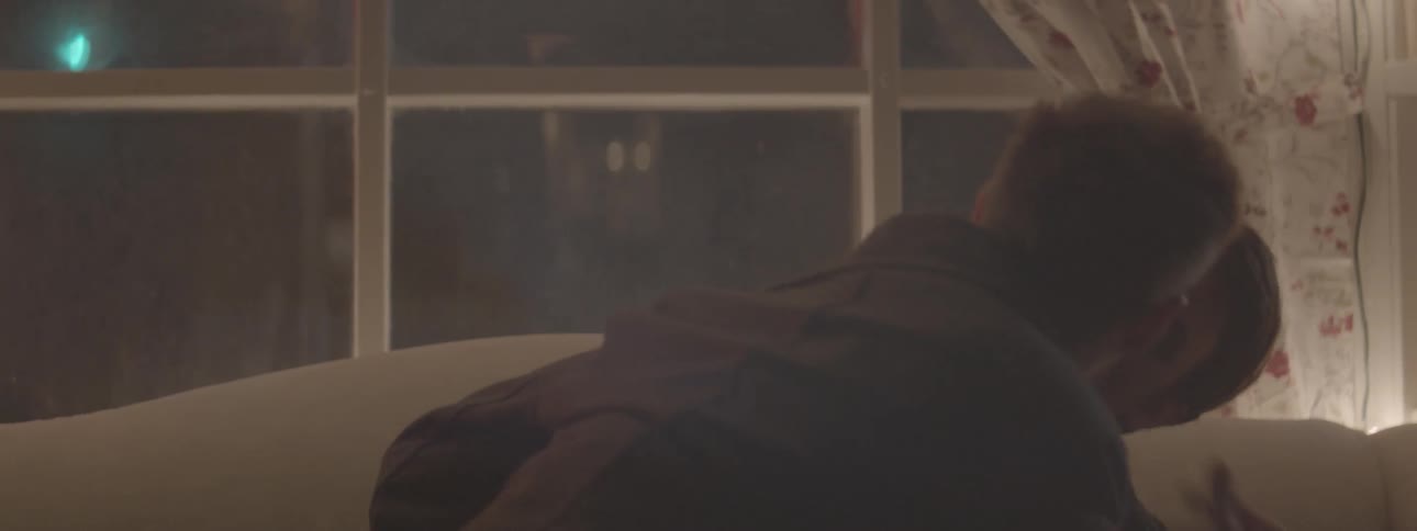 A couple kiss on a couch