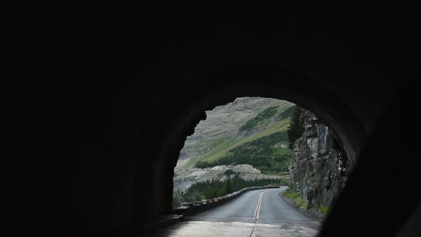 A car drives through a tunnel toward a mountain