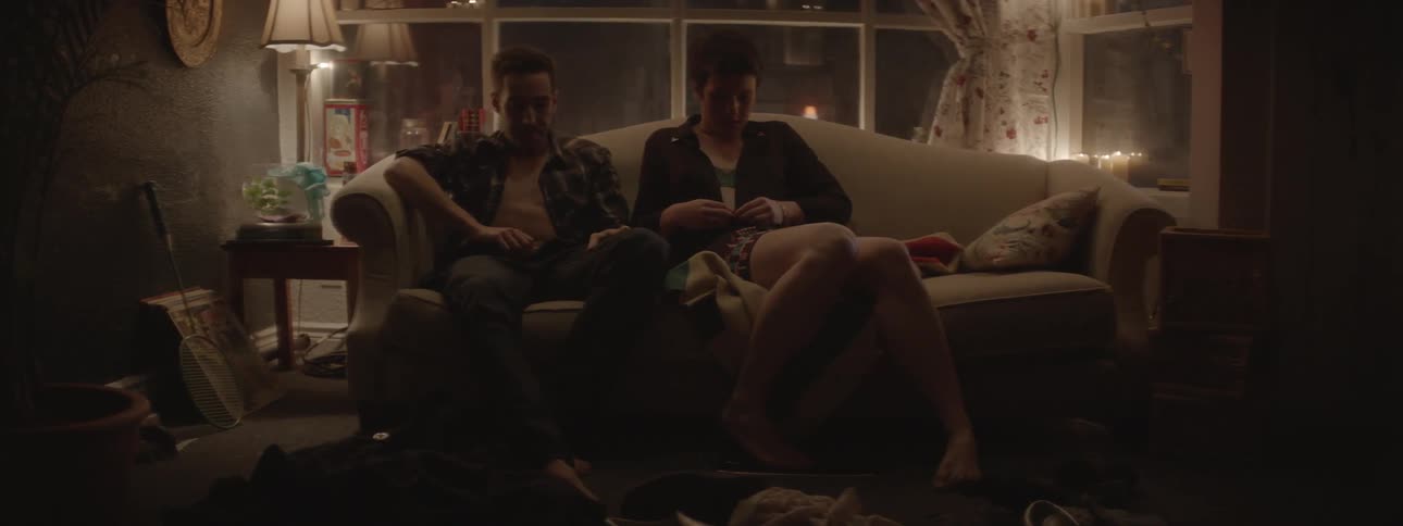 A man and woman sit on the couch talking