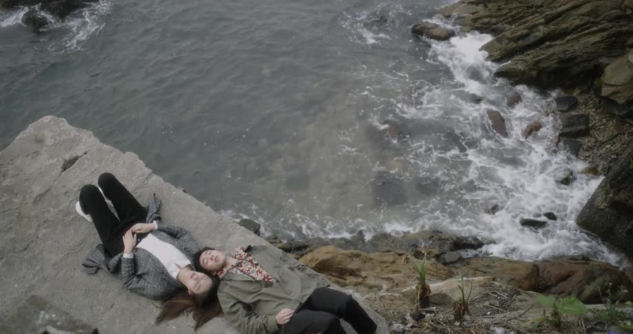 A man and woman lay down together by the shore
