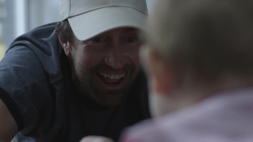 A man is laughing as he talks to a baby