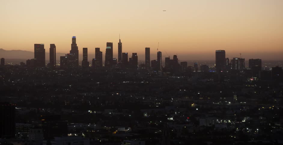 City skyscrapers stand against the sky at sunset