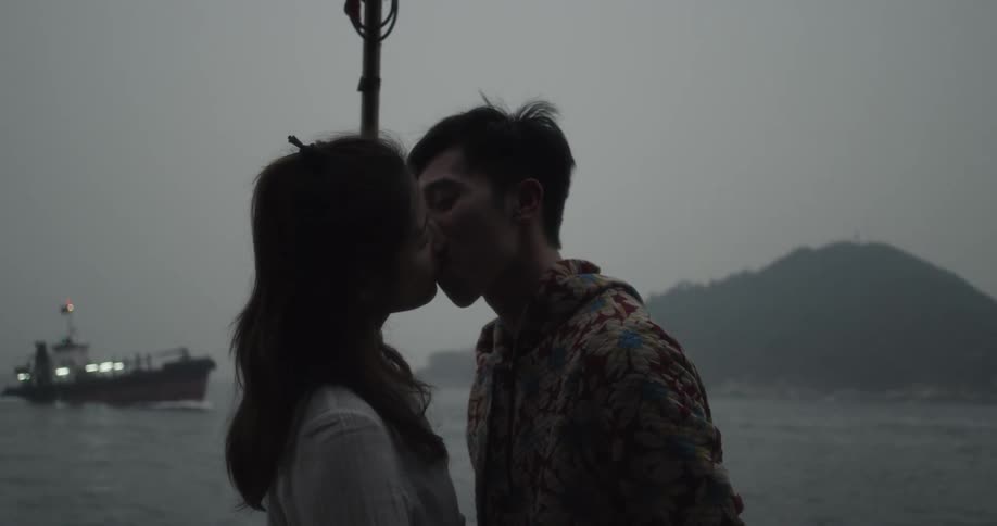 A man and woman kiss on the coast