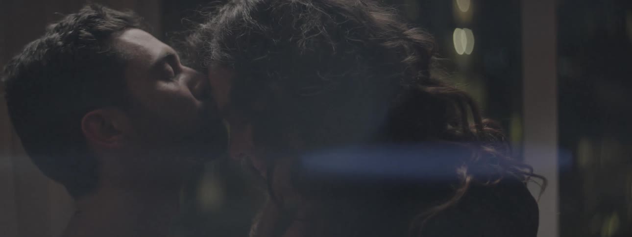 A man and woman kiss near a window
