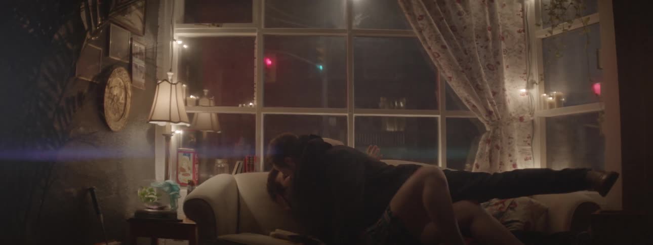 A kissing couple fall onto a couch