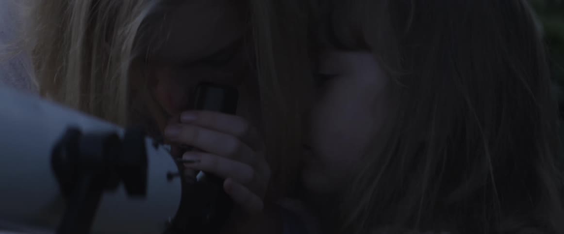 A woman moves so a girl can look through the telescope