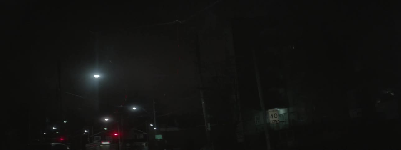 People are traveling in cars down the dark road