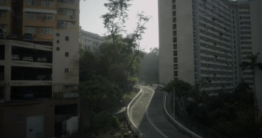 A city road winds by apartment buildings