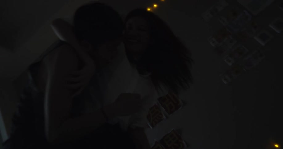 A couple play wrestle in a dim bedroom