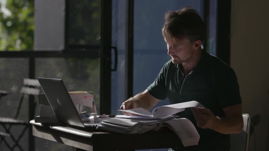 A man is working flipping papers on his desk