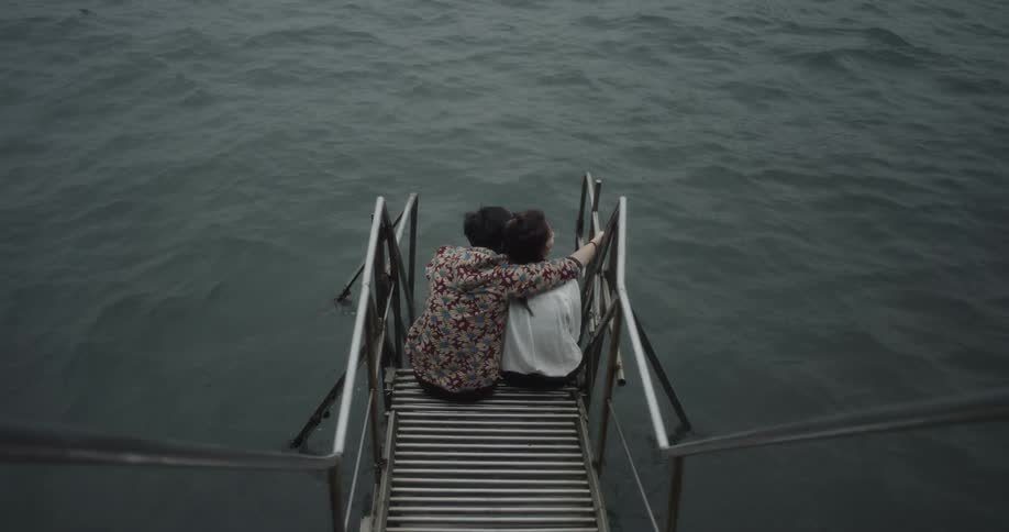 A man and woman sit by the water