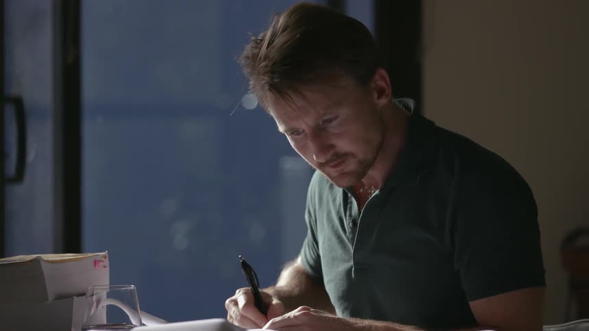 A man is writing at his desk