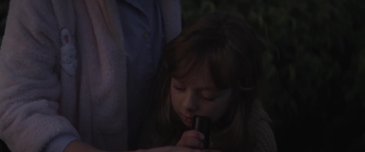 A little girl looks into a telescope