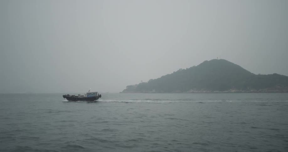 Boat traveling across ocean waters on overcast day