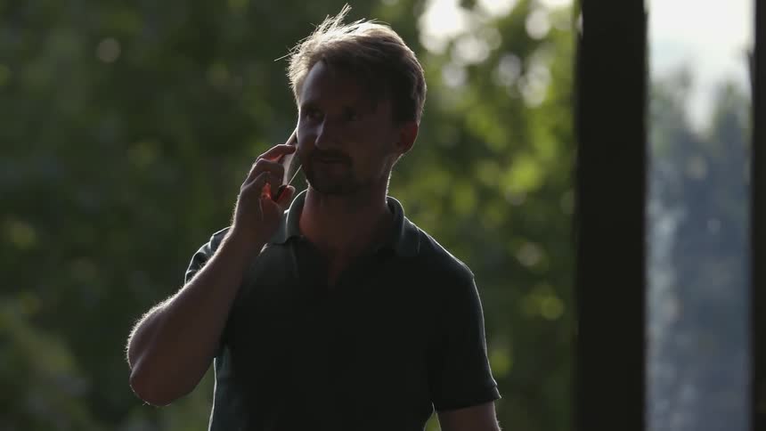 Man talks on his phone outside of a house