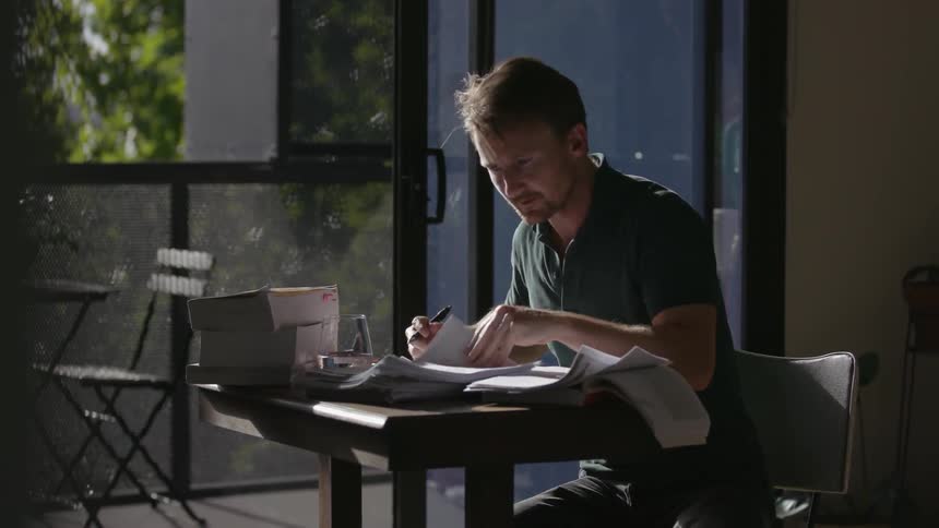 A man hangs up his phone and goes back to paperwork