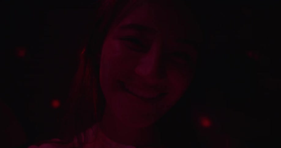 A woman is smiling as she spins in the dark