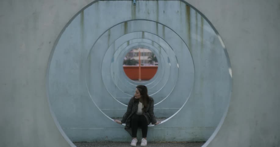 A woman walks past some circles then sits down