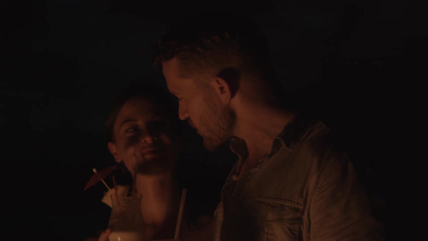 Man and woman talk and hold drinks in the firelight