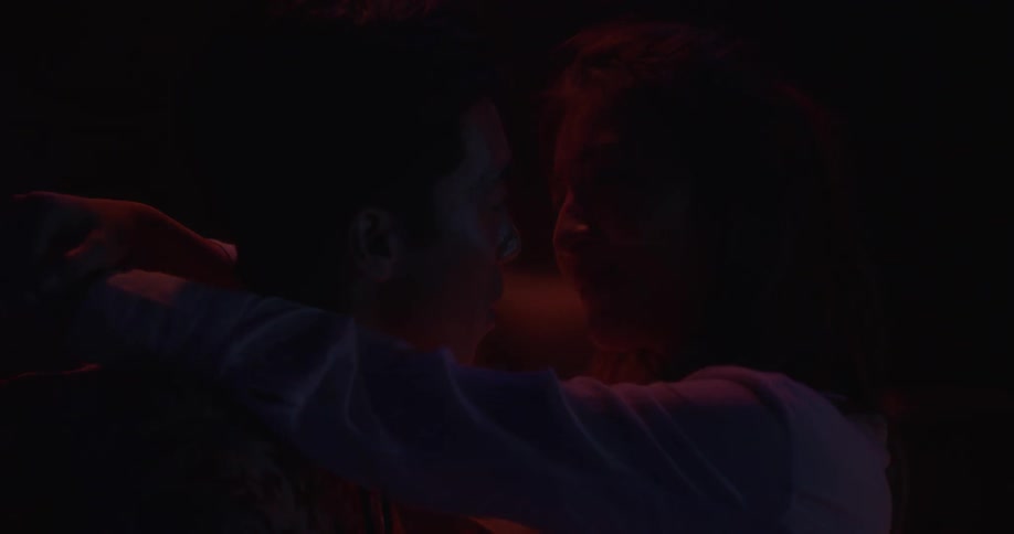 A man and woman dance and talk in the dark