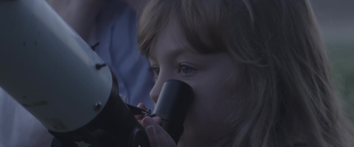 Little girl looking into telescope