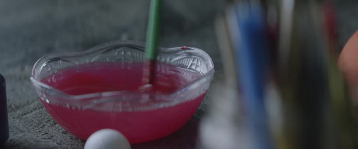 A person rinses a paint brush in water