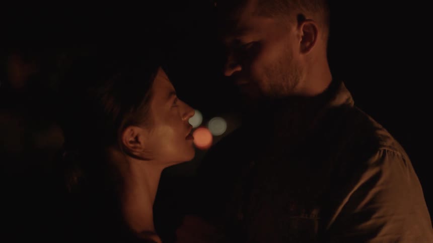 A couple kiss near a fire