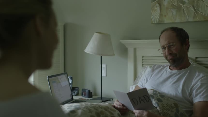 A man is smiling as he reads a card given to him