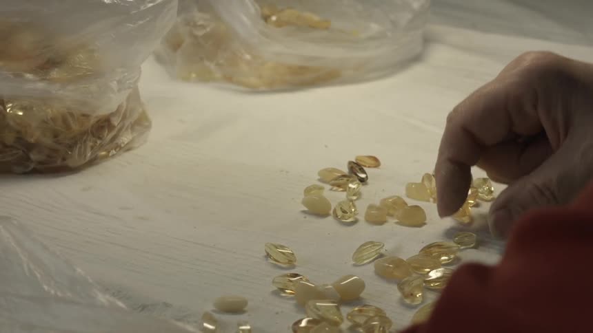 A woman sorts gemstones and places them in bags