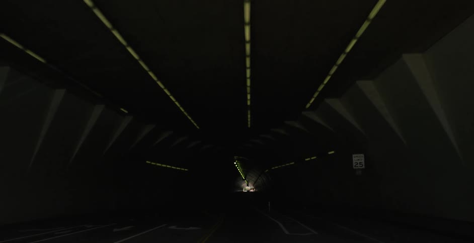 Vehicles travel through a tunnel in an urban area during the day