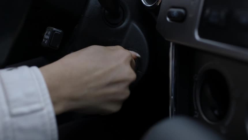 Woman turning a key in the ignition of a vehicle