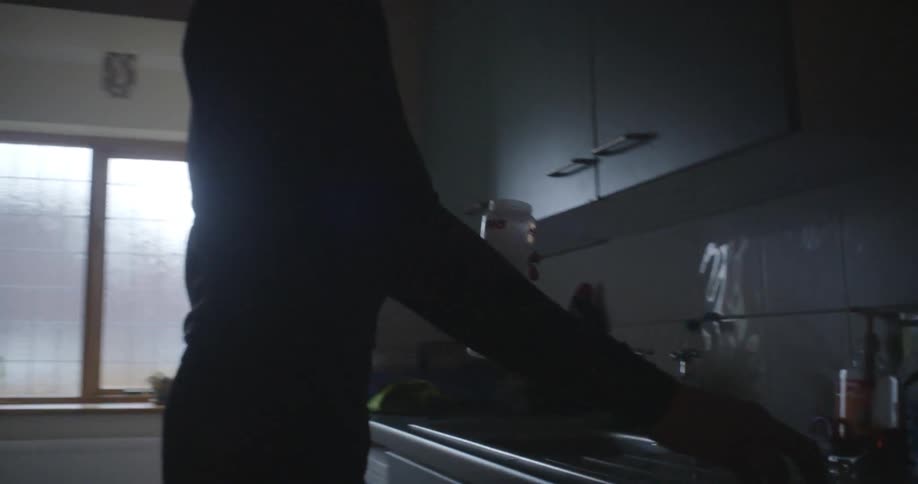 Person fills a bottle with water at a kitchen sink