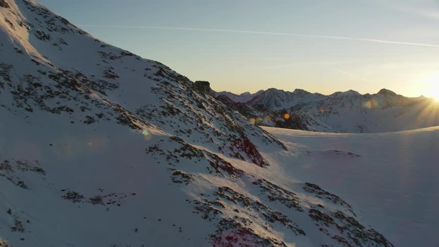 The sun shines on snow covered mountain peaks