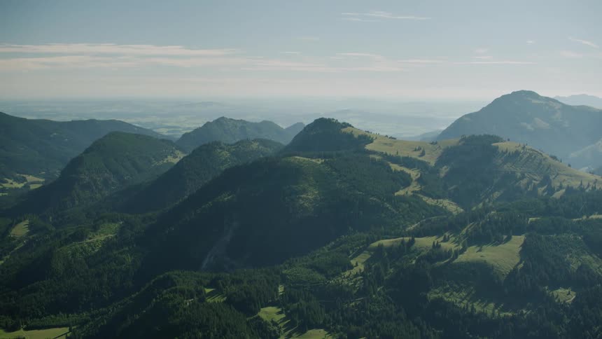 The hills are covered with green and light fog ahead