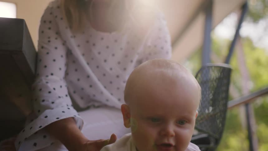 A woman is holding a baby up on the floor