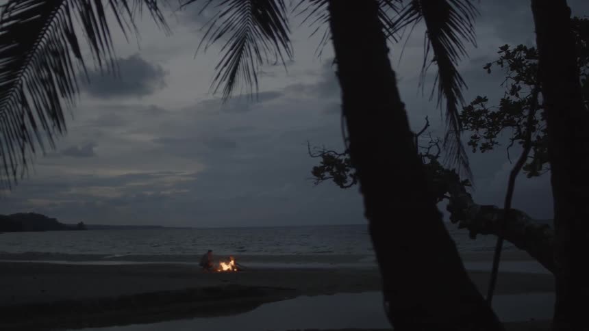 A man kneels in front of a fire