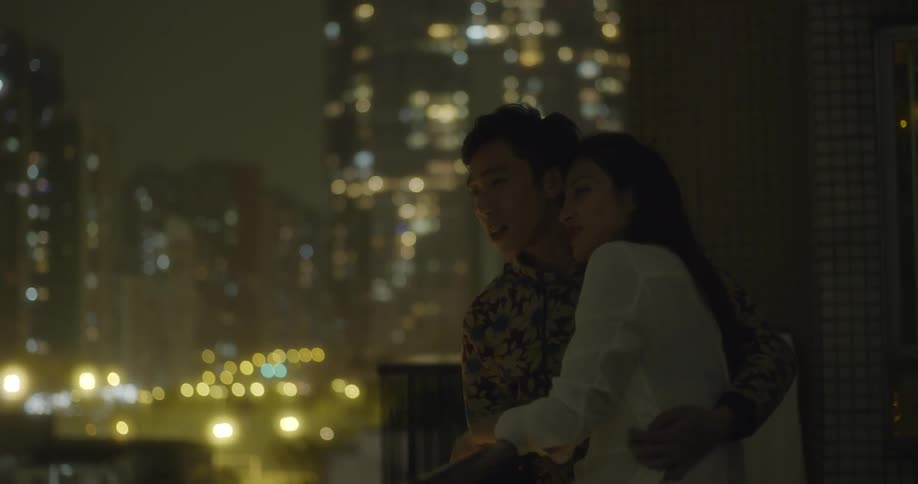A man and woman hug at night on the rooftop
