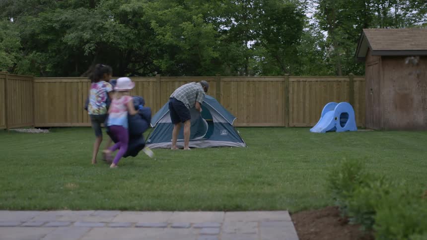 A man unzips a tent in the backyard