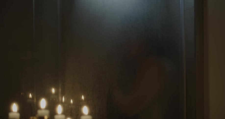 A person is in the shower with candles lit outside