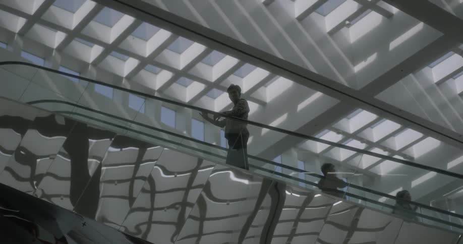 A man rides the escalator up looking over the side