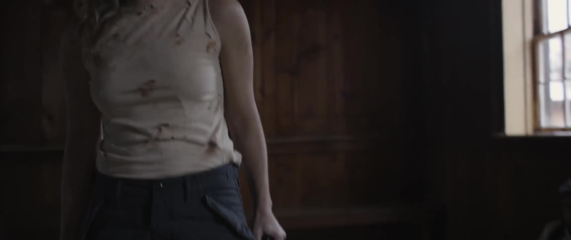A woman holding a gun stands up and walks toward a man on a table